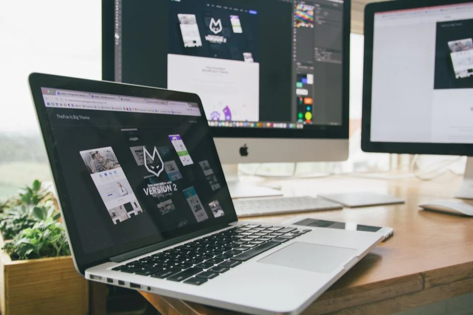 A photographer working at a creative setup with a laptop and Wacom tablet, focused on editing photos indoors.